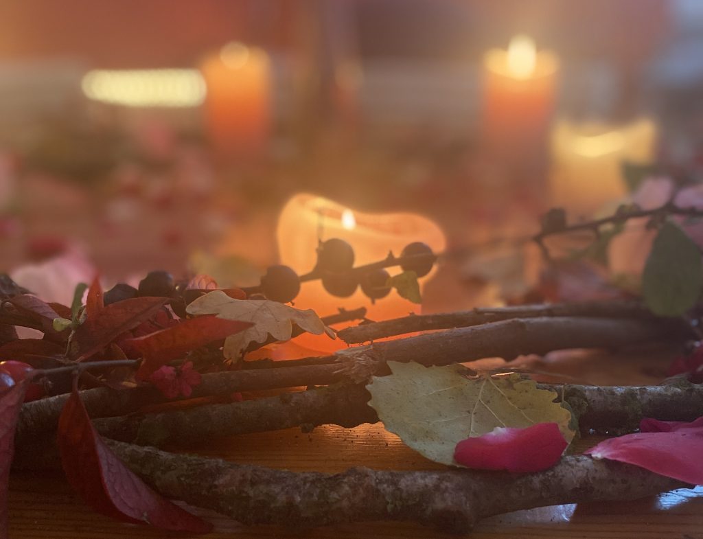 Zweige, Blätter und Blüten im Kerzenschein, auf Holzfußboden.