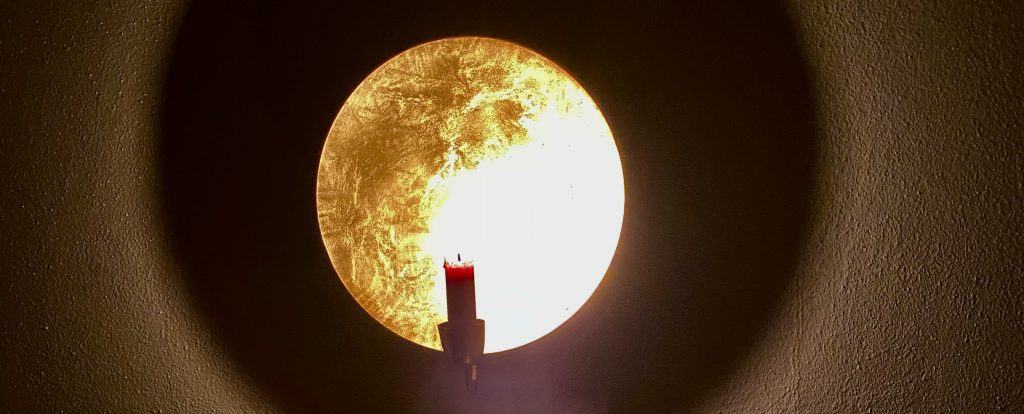 Kerze vor goldenem Hintergrund