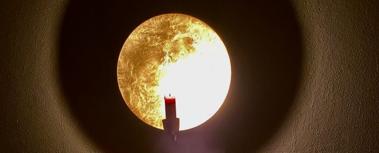 Kerze vor goldenem Hintergrund